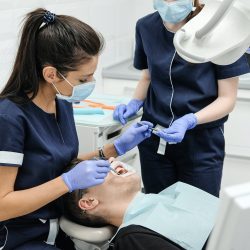 Dentista con ayudante examinando la boca de un paciente